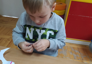 Dziecko wykonuje ozdobę choinkową z papieru